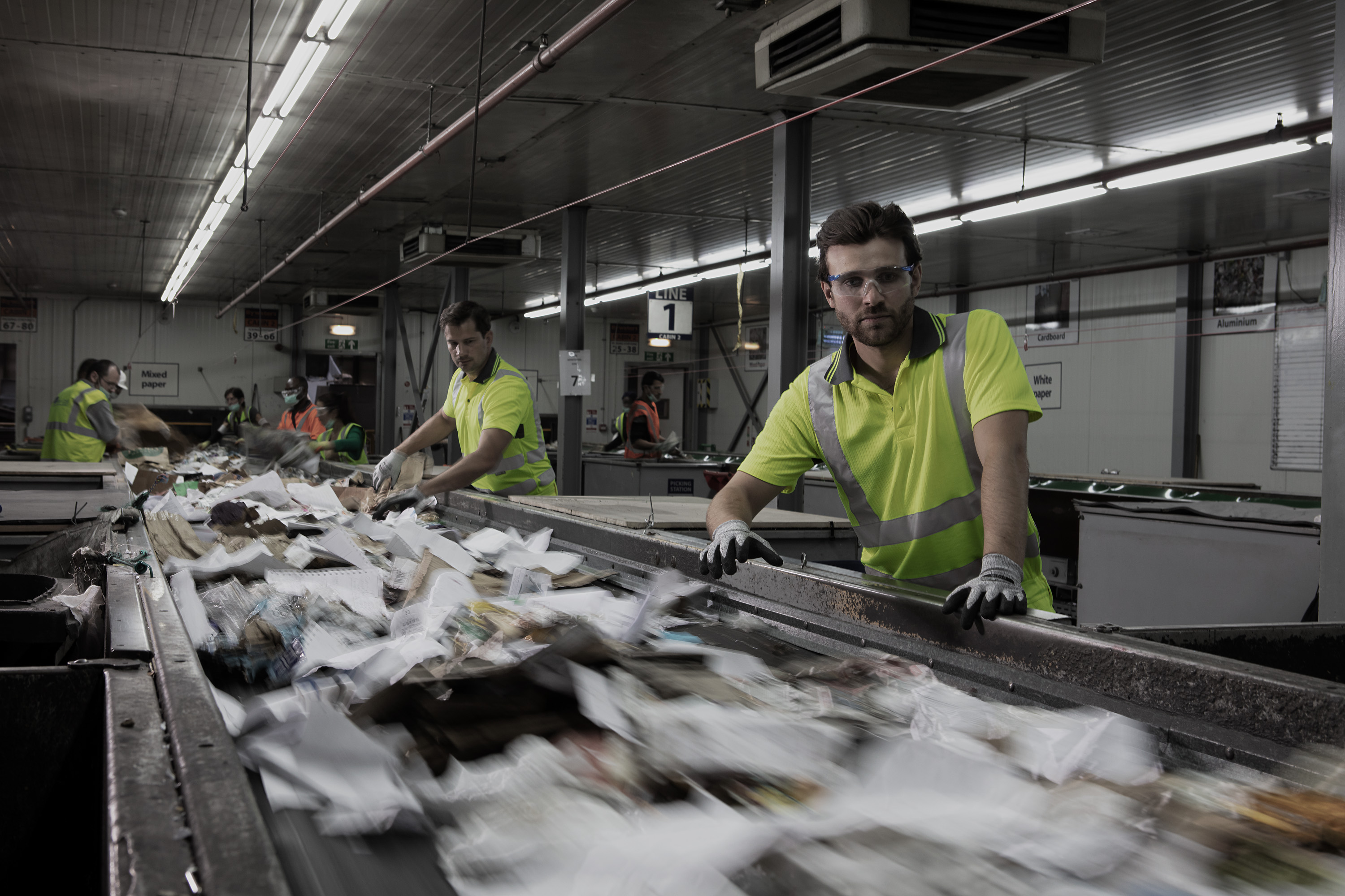 Men wearing safety workwear in recycling centre